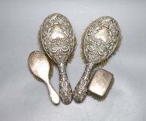 A pair of Edwardian repousse silver backed hair brushes and two other brushes.
