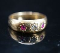 An early 20th century yellow metal and gypsy set ruby and diamond set three stone ring, size O,