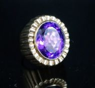 A yellow metal and oval cut amethyst set dress ring, with fluted setting, size Q/R, gross 17 grams.