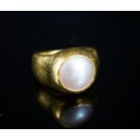 A planished yellow metal (inscribed 24k) and mother of pearl mounted ring, indistinctly signed, size