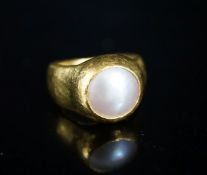A planished yellow metal (inscribed 24k) and mother of pearl mounted ring, indistinctly signed, size