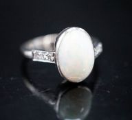 A white metal and white opal set oval ring, with diamond set shoulders, size M, gross weight 3.4