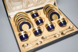 A cased set of six Limoges coffee cups and saucers, six silver gilt spoons