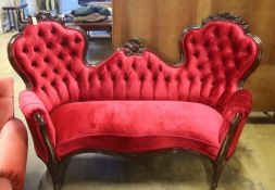 A Victorian carved rosewood double spoon back settee upholstered in deep buttoned scarlet velvet,