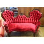 A Victorian carved rosewood double spoon back settee upholstered in deep buttoned scarlet velvet,