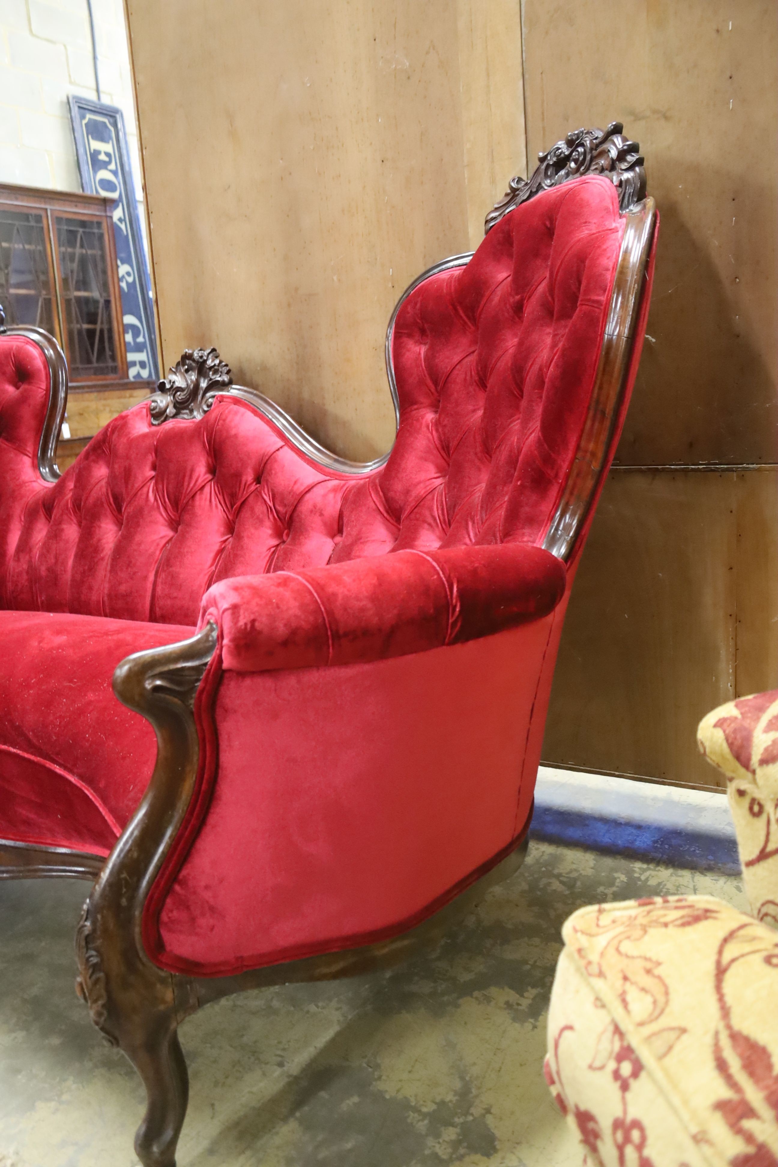 A Victorian carved rosewood double spoon back settee upholstered in deep buttoned scarlet velvet, - Image 5 of 5