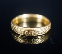 A George V bright cut engraved 22ct gold wedding band, decorate with flower heads, London, 1918,