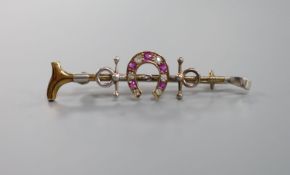 A late Victorian yellow metal, ruby and diamond set horseshoe and riding crop bar brooch, 50mm,