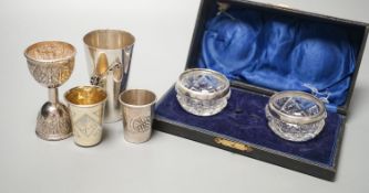 Two early 20th century Russian white metal tots, a sterling beaker, white metal double measure and a