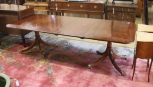 A reproduction George III style mahogany twin pillar extending dining table, two spare leaves,