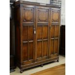 A carved and panelled oak triple wardrobe with fitted interior, length 150cm, depth 49cm, height