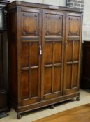 A carved and panelled oak triple wardrobe with fitted interior, length 150cm, depth 49cm, height