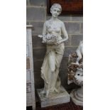 A large painted composition faux marble garden ornament, modelled as a girl with basket of fruit,
