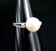 A white metal and single stone cultured pearl dress ring, with diamond set shoulders, size L/M,