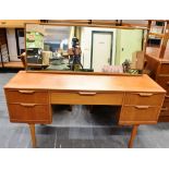 AN AUSTINSUITE TEAK DRESSING TABLE with central drawer flanked by pair of drawers, 137cm wide 42cm