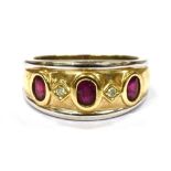 A RUBY THREE STONE 18CT YELLOW AND WHITE GOLD BAND RING with two small round cut diamonds between,