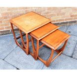 A G-PLAN NEST OF THREE TEAK TABLES the largest 50cm square, 51cm high; together with a glass and