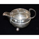 AN A.E. JONE'S ARTS AND CRAFTS DESIGN SILVER MILK JUG The couldren shape jug with hammered finish on