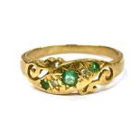 A 9CT GOLD SMALL EMERALD SET DRESS RING the scroll work front diagonally set with three very small