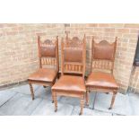 A SET OF FOUR CARVED OAK FRAMED DINING CHAIRS with leather upholstered seats and backs