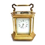 A BRASS CASED CARRIAGE CLOCK of hexagonal form, the shaped sides with enamelled decoration of