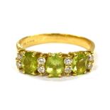 AN 18CT GOLD PERIDOT THREE STONE RING with pairs of small diamonds between, the three oval cut