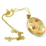 A MODERN 9CT GOLD OVAL LOCKET AND CHAIN the embossed flower spray to the front with red and white