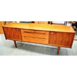 A 1970S YOUNGER TEAK SIDEBOARD fitted with three central drawers flanked by cupboards, on tapering