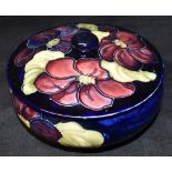 A MOORCROFT POTTERY LIDDED BOWL decorated in the 'Clematis' pattern on a blue ground, paper