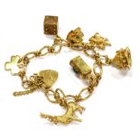A 9CT GOLD CHARM BRACELET with padlock fastener and seven assorted charms, the padlock fastener