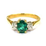 AN EMERALD AND DIAMOND THREE STONE 18CT GOLD RING the central oval cut emerald approx. 7.1 x 5.