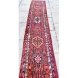 A RED GROUND RUNNER with seven medallions, 63cm x 317cm Condition Report : no great age, but good