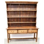 19TH CENTURY WELSH OAK DRESSER, with mounted plate rack top and pannelled back, above three drawers,