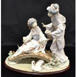 A LARGE LLADRO GROUP MODELLED AS TWO JAPANESE GEISHAS ON A BRIDGE 30cm high, on a matching base