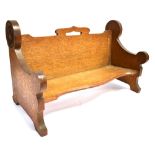 AN ARTS AND CRAFTS OAK BOOK TROUGH with a floral carved decoration to each side, a small carrying