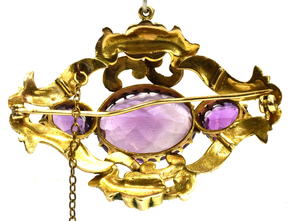 AN AMETHYST THREE STONE SCROLL WORK BROOCH the centre oval amethyst 20mm x 15mm the yellow metal - Image 2 of 2