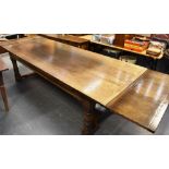 A LARGE OAK EXTENDING DINING TABLE the three plank top with cleated ends, raised on substantial