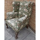 A GEORGE III STYLE UPHOLSTERED WING ARMCHAIR probably late 19th century, in a William Morris style