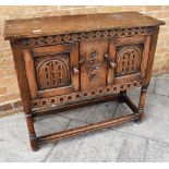 A SMALL CARVED OAK CUPBOARD ON STAND the panelled doors with wood catches, the turned supports