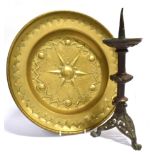 A BRASS ALMS DISH with embossed and chased decoration, 40.5cm diameter; and a pricket candlestick on