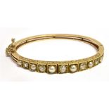 AN EDWARDIAN DIAMOND AND PEARL SET GOLD BANGLE the graduating front section comprising five round