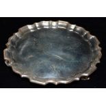 A SMALL SILVER SALVER On three scroll feet, of hammered finish with plain central cartouche and