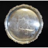 A SILVER PRESENTATION SALVER the round tray with scroll boarder on three pad feet, central