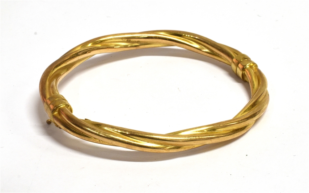 A 9CT GOLD HINGED BANGLE the barley twist design of hollow construction with sprung clasp,