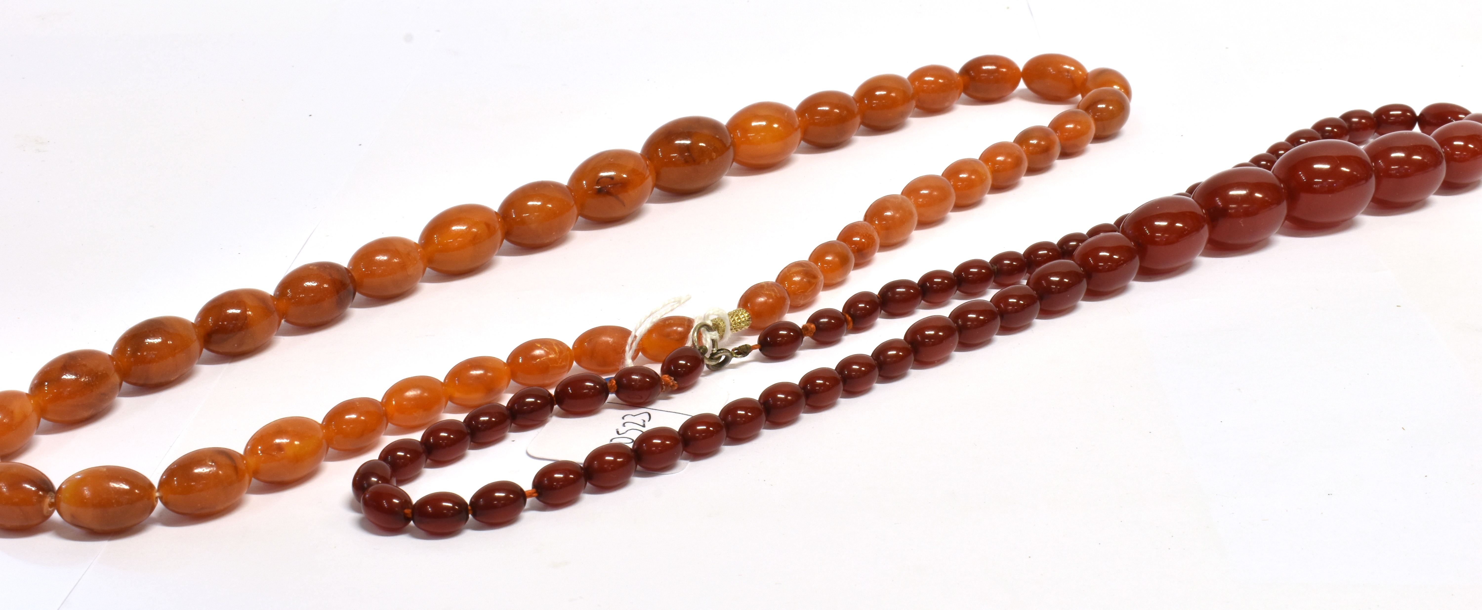 TWO AMBER TYPE BEAD NECKLACES both with graduating oval beads, one with butterscotch colour, the