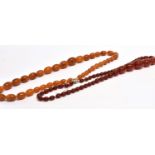 TWO AMBER TYPE BEAD NECKLACES both with graduating oval beads, one with butterscotch colour, the