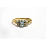 AN AQUAMARINE AND DIAMOND SET GOLD RING the central oval cut aquamarine approx. 6 x 4mm with six