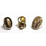 THREE SILVER STONE DRESS RINGS comprising a smokey quartz single stone, a garnet set three stone and