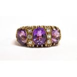 AN AMETHYST THREE STONE 9CT GOLD RING Three oval cut amethyst, the centre stone approx. 8mm x 6 mm