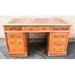 AN OAK TWIN PEDESTAL DESK, having a leather writing surface and a central long drawer flanked by two